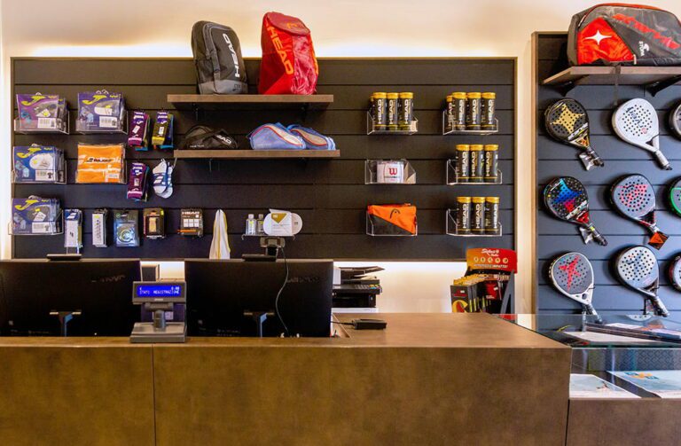 Punto cassa di un negozio di articoli sportivi con espositori modulabili in base alle diverse esigenze di prodotto (in questo caso racchette per padel, borsoni, accessori)