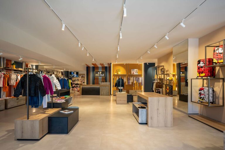 Foto panoramica negozio abbigliamento ragazzi e bambini con focus sulla zona ragazzi
